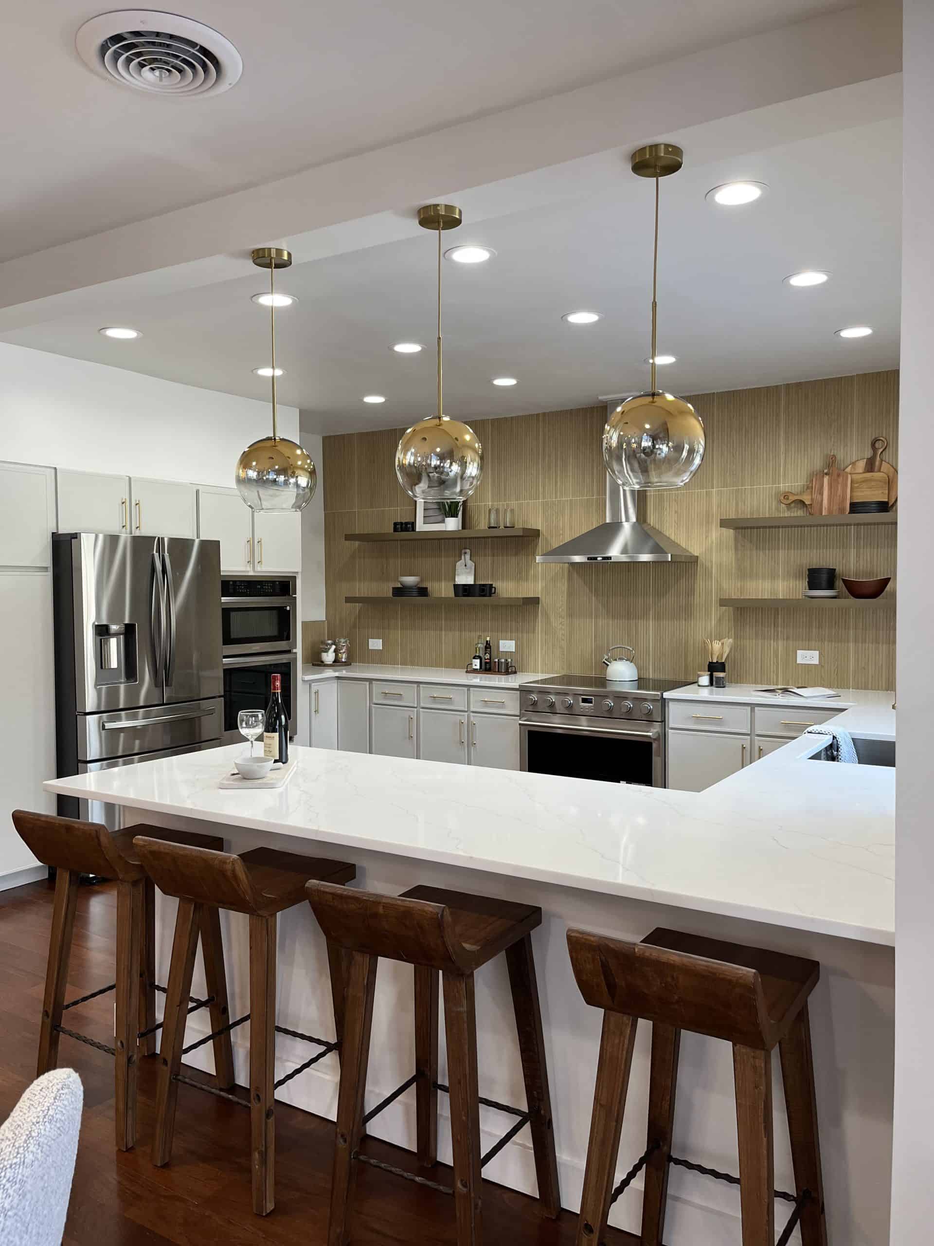 Interior kitchen painting Colorado Springs – modern kitchen with white cabinets, wood accents, and pendant lights